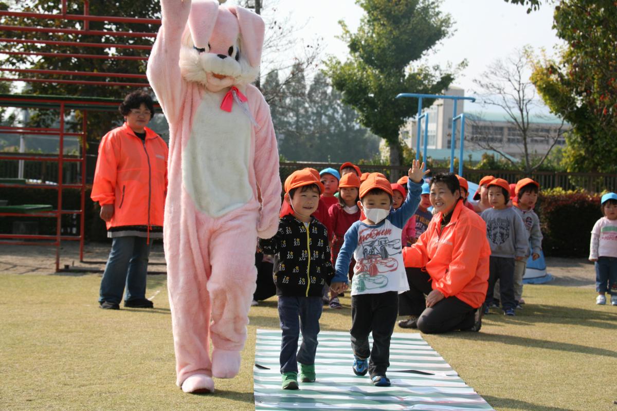 園庭に設置された模擬横断歩道を、うさぎの着ぐるみと一緒に渡る子どもたち