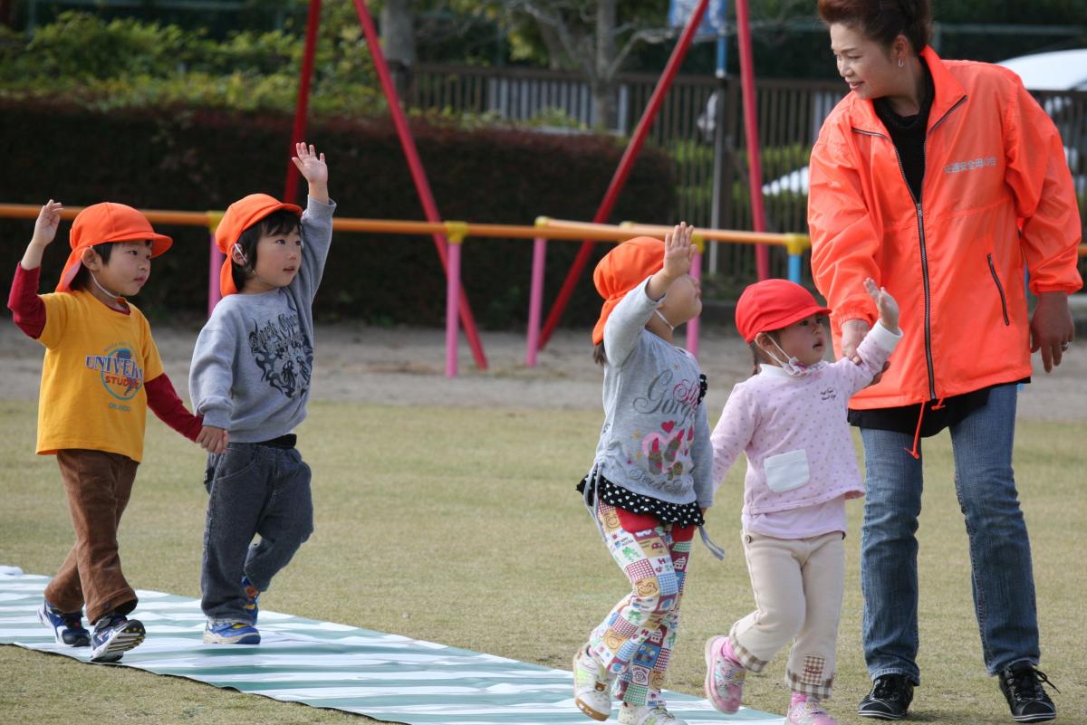 交通安全母の会のメンバーと手をつないで横断歩道を渡る子どもたち