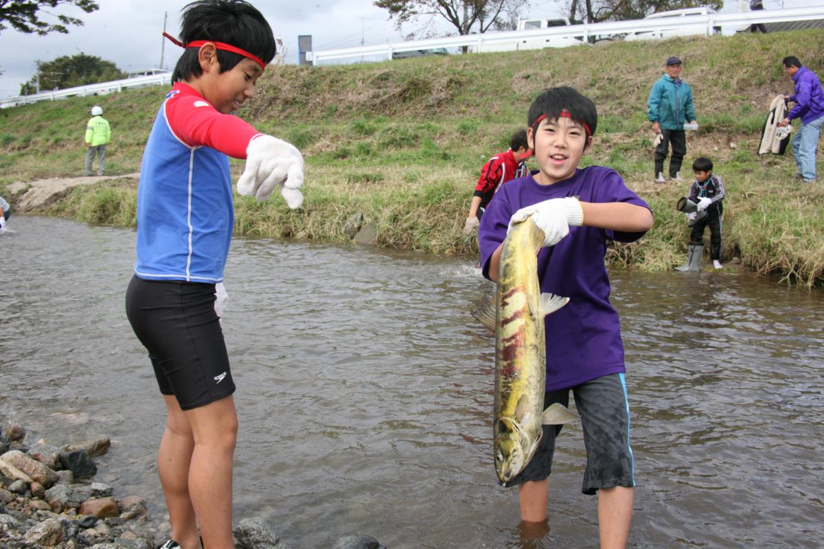 大きなサケをつかみ取りして大満足の表情を浮かべる子どもたち