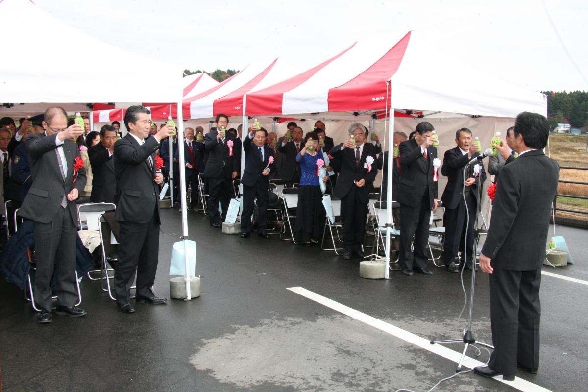 地域住民など関係者約80人で乾杯し、開通を祝う様子