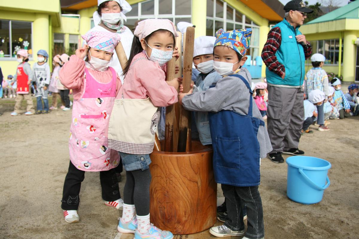 力強くおもちをついて笑顔を見せる園児