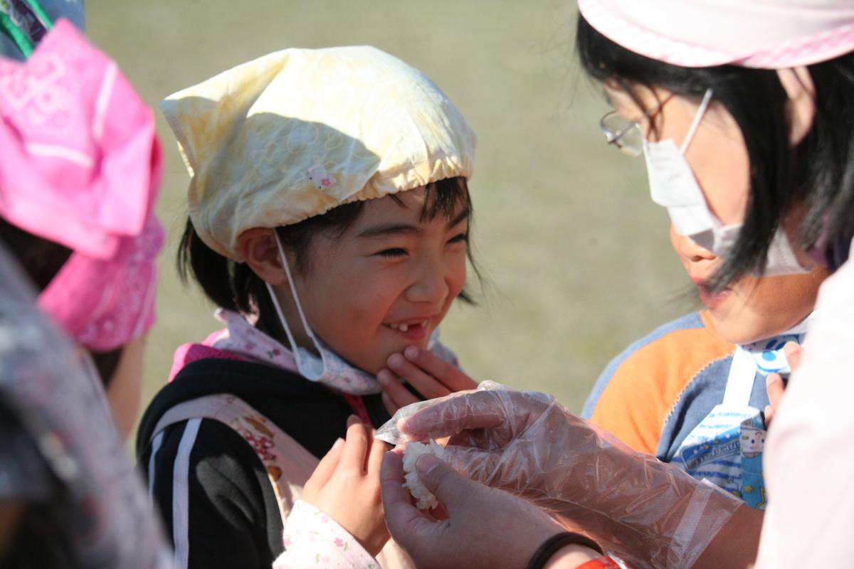 蒸かしあがったもち米を食べてとても美味しそうに笑う園児