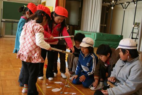 手作りの釣り遊びに夢中になる園児と、それを見守る小学生