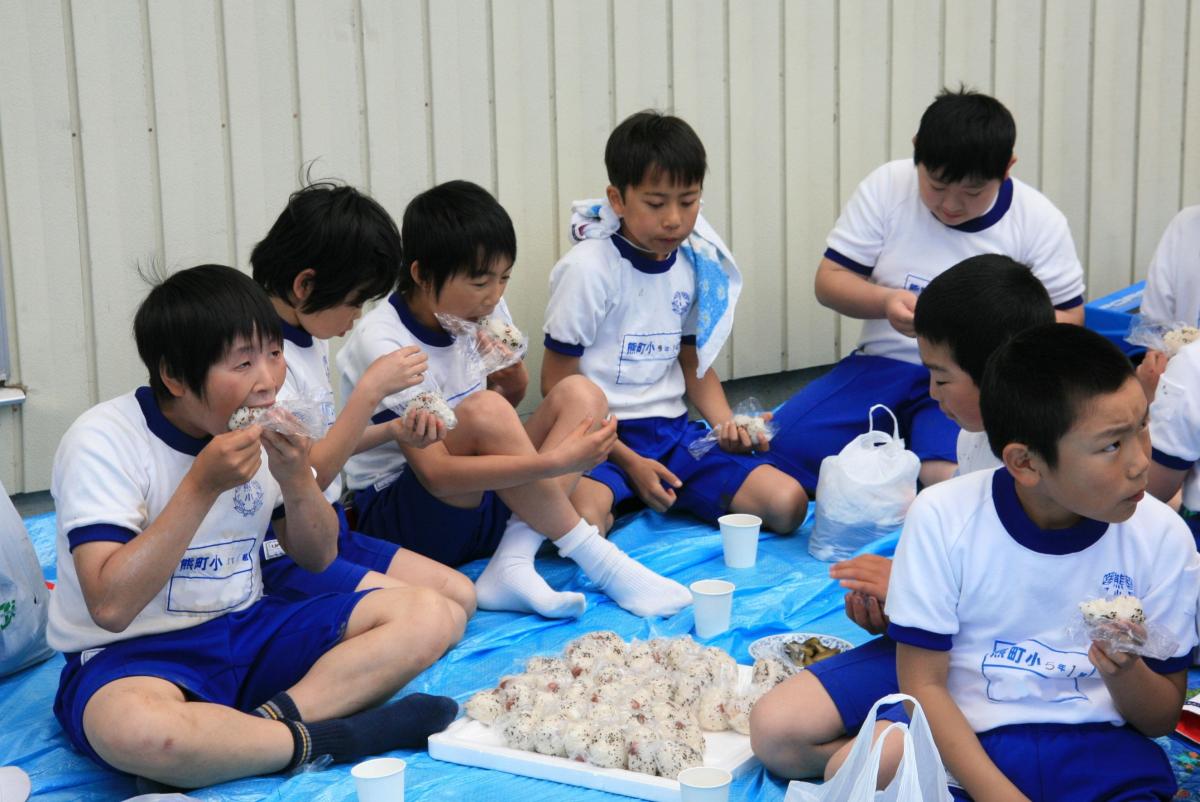 大きな口を開けて美味しそうにおにぎりを食べる児童たち