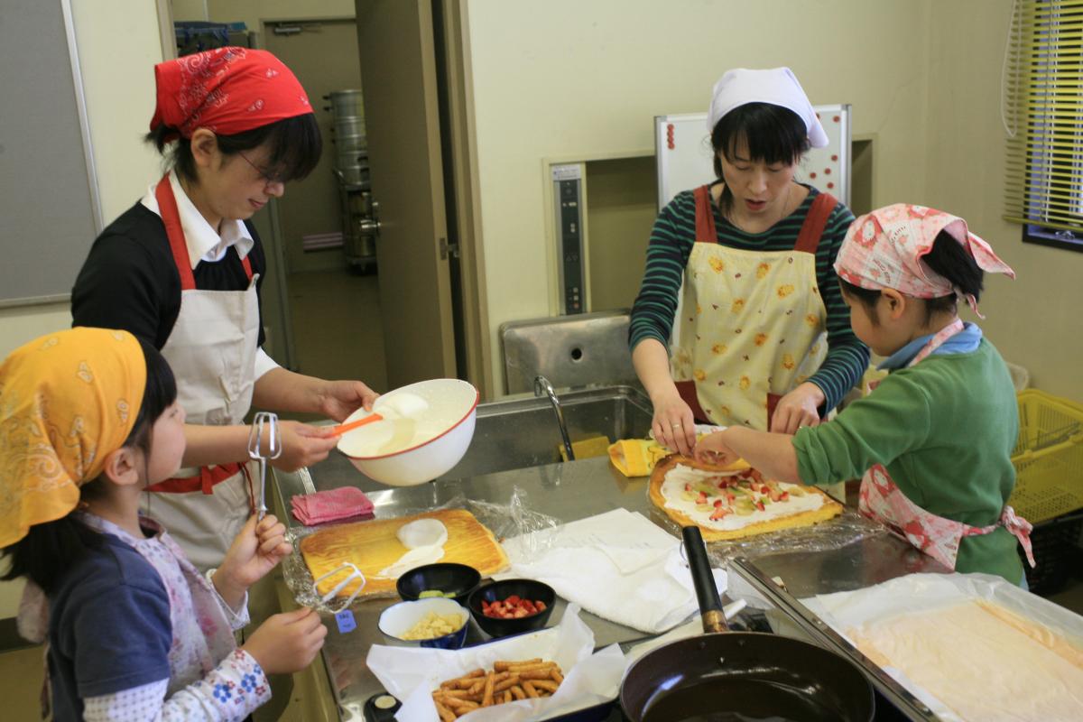 真剣な表情でロールケーキを巻く親子