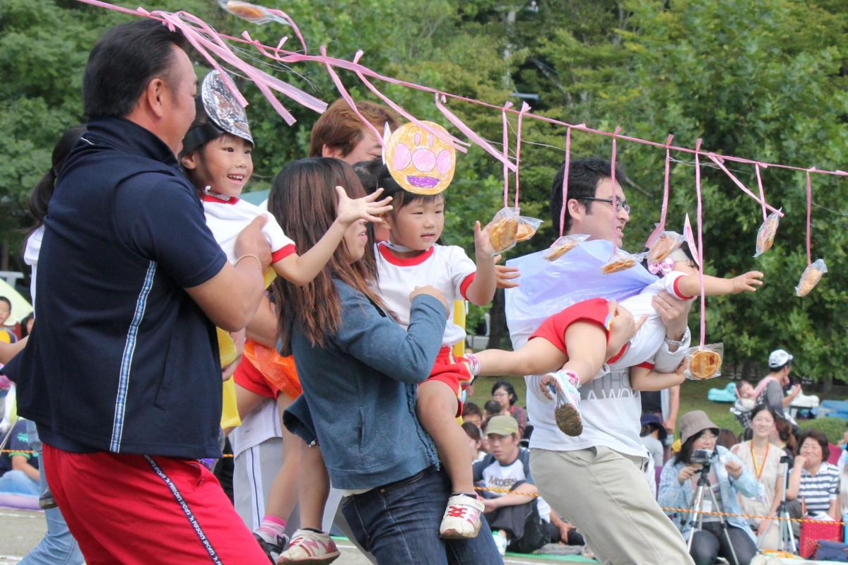 お父さん、お母さんに抱っこしてもらいおせんべいを取る園児