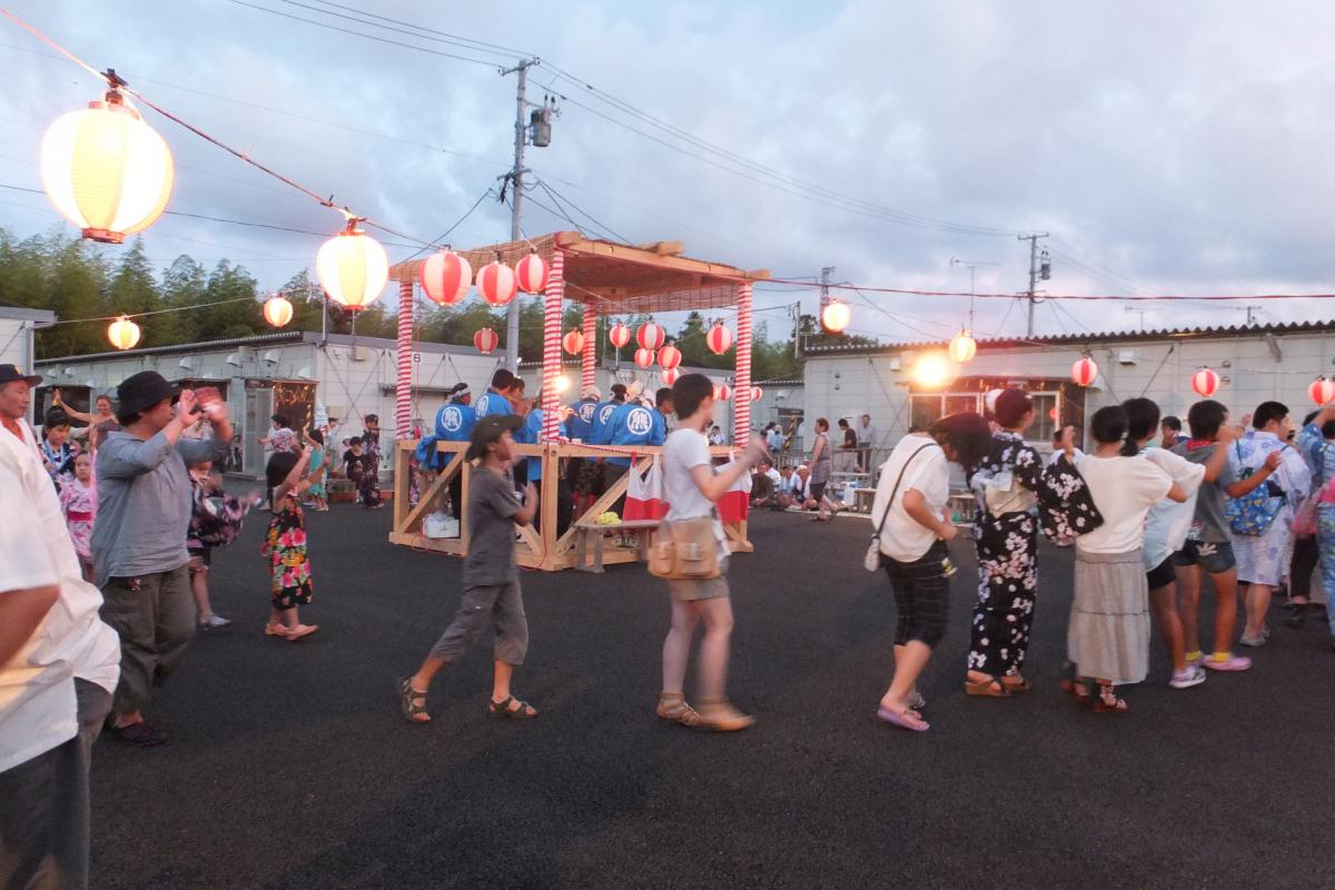 笛や太鼓に合わせて盆踊りを楽しむ町民たち