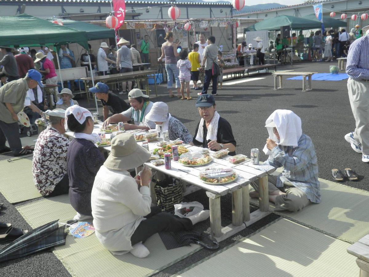 笛や太鼓が鳴り響く会場で食事を楽しむ町民たち