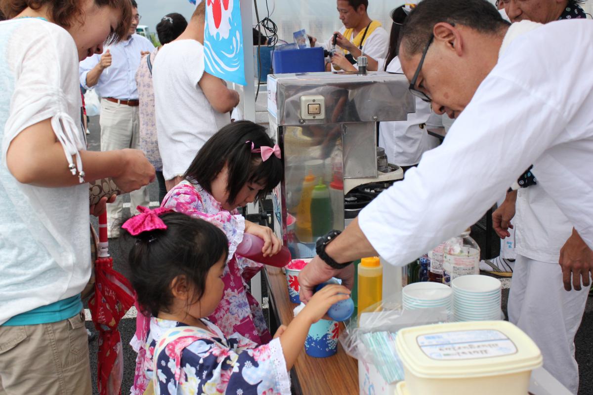 屋台でかき氷を買い、嬉しそうにシロップをかける子どもたち