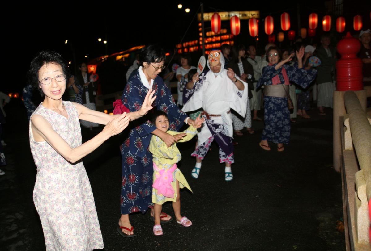 東山温泉を流れる湯川の上に建てられたやぐらの周りで、拍子に合わせて盆踊りを踊る参加者