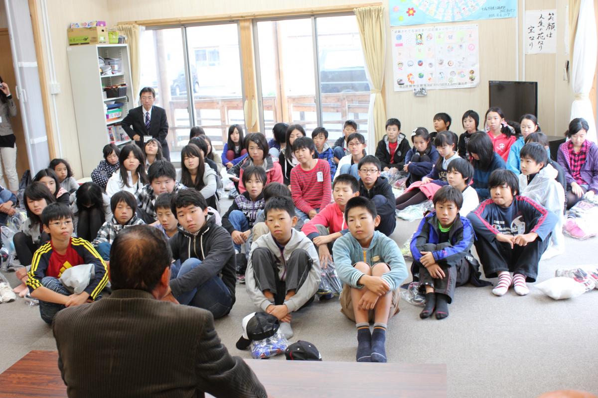 集会所で行われたふれあいタイムで自治会長から大熊町民の避難の現状の話をされ、聞き入る子どもたち