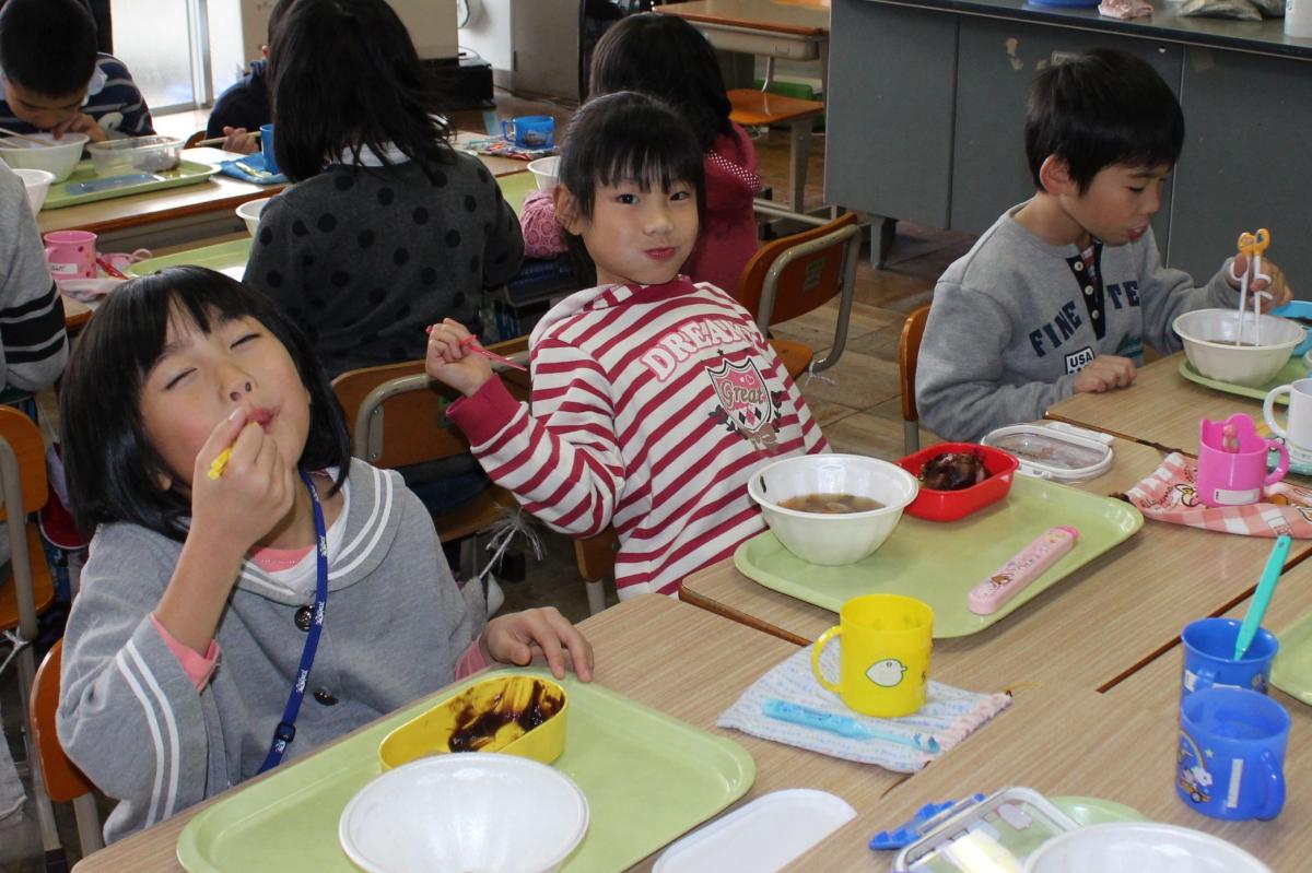 できあがったもちを頬張り美味しそうに笑う小学生