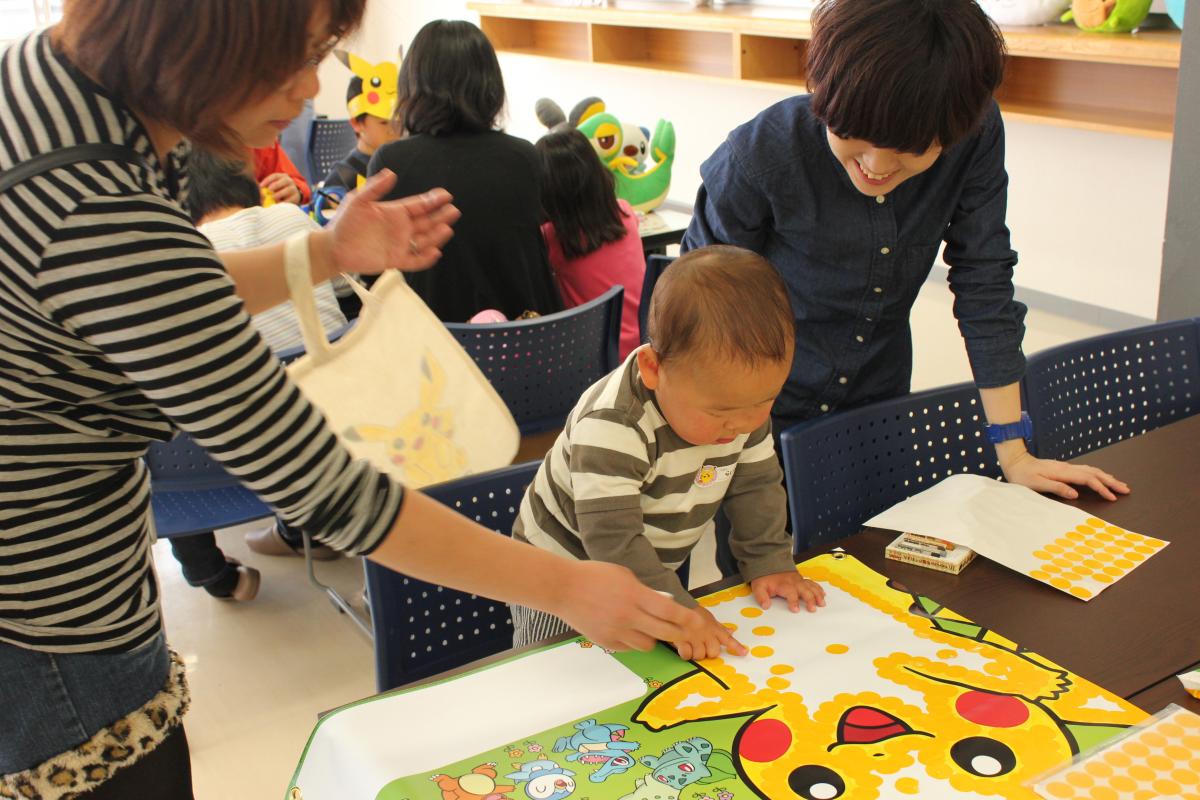 黄色いシールをたくさん貼ってピカチュウを染めていく赤ちゃん