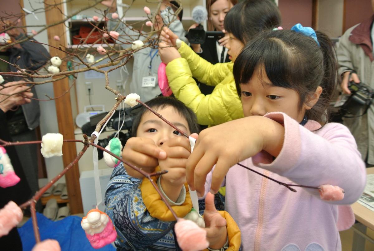 ミズキの枝に餅や縁起物を付ける小正月の伝統行事「稲穂つけ」を行う来場者