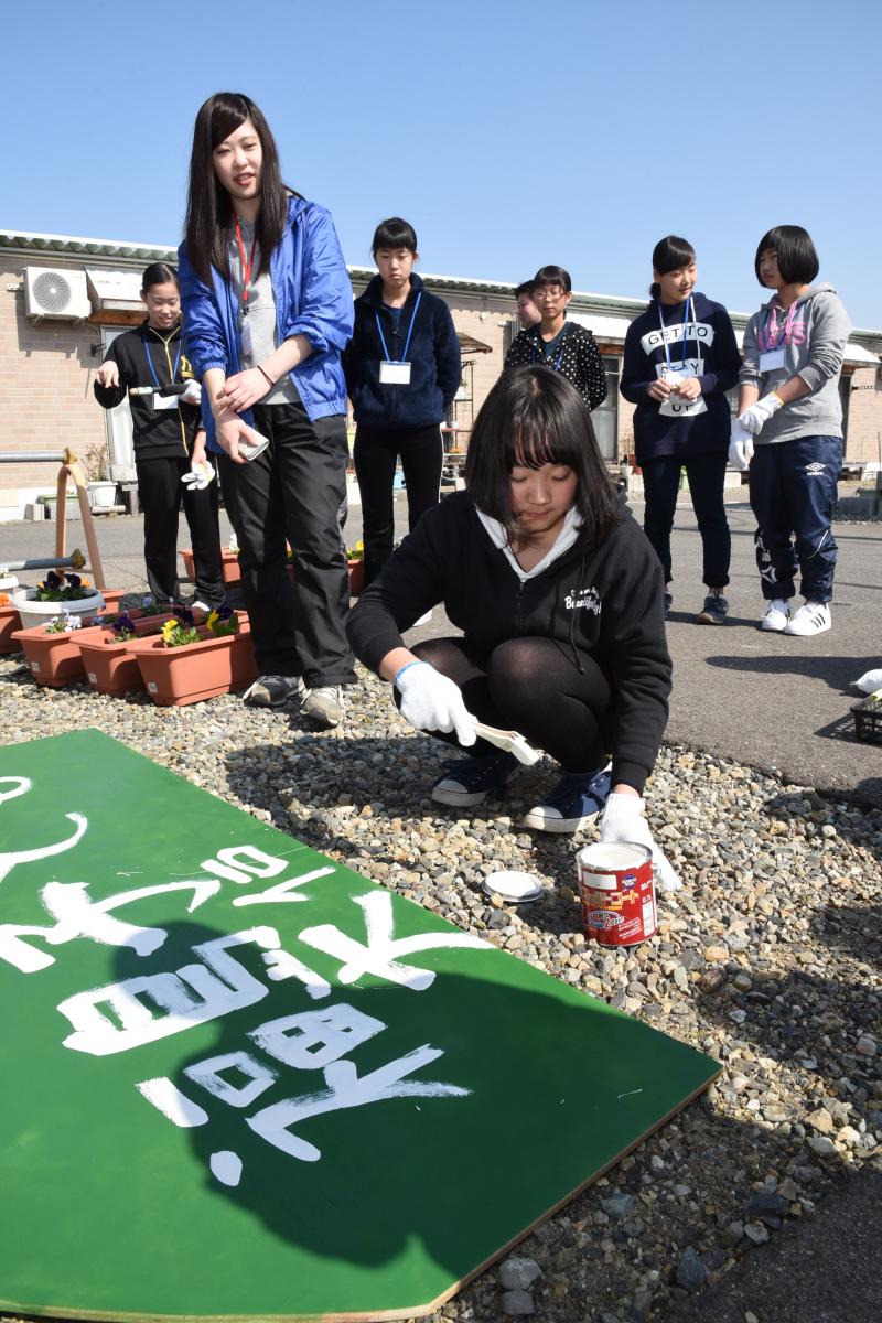 集会所前に作った記念の花壇に置く看板を作成する中学生