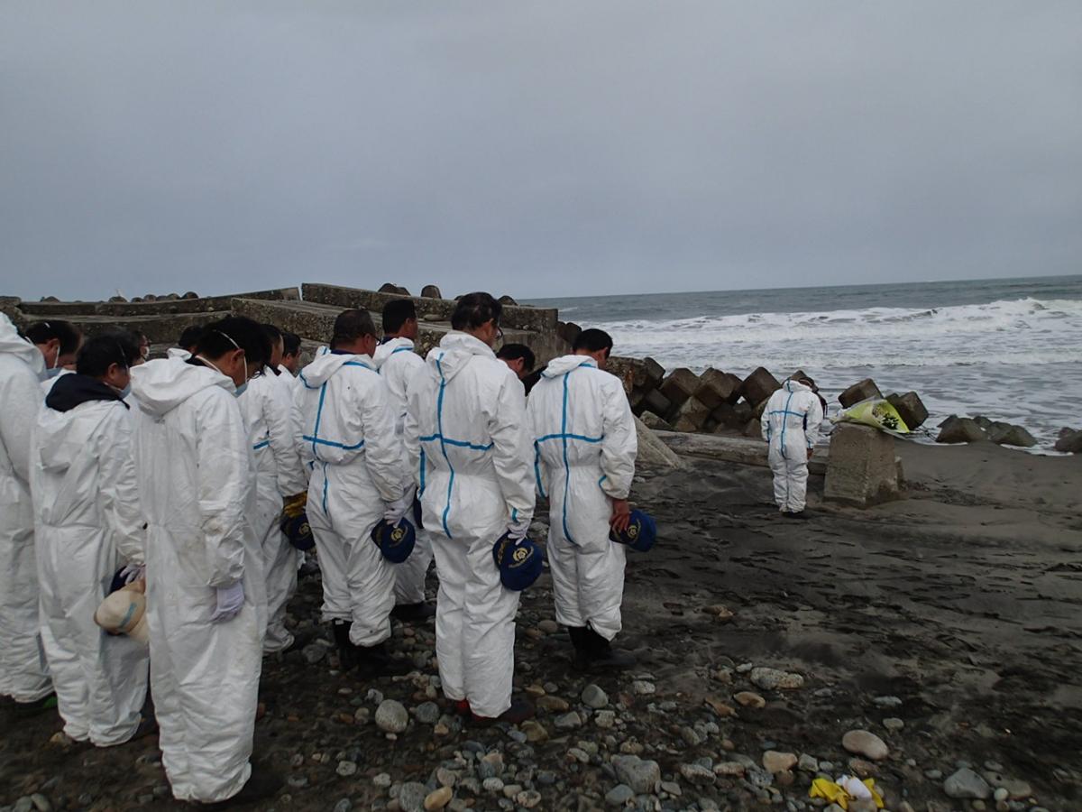 海に向かい祈りを捧げる消防団員、警察ら