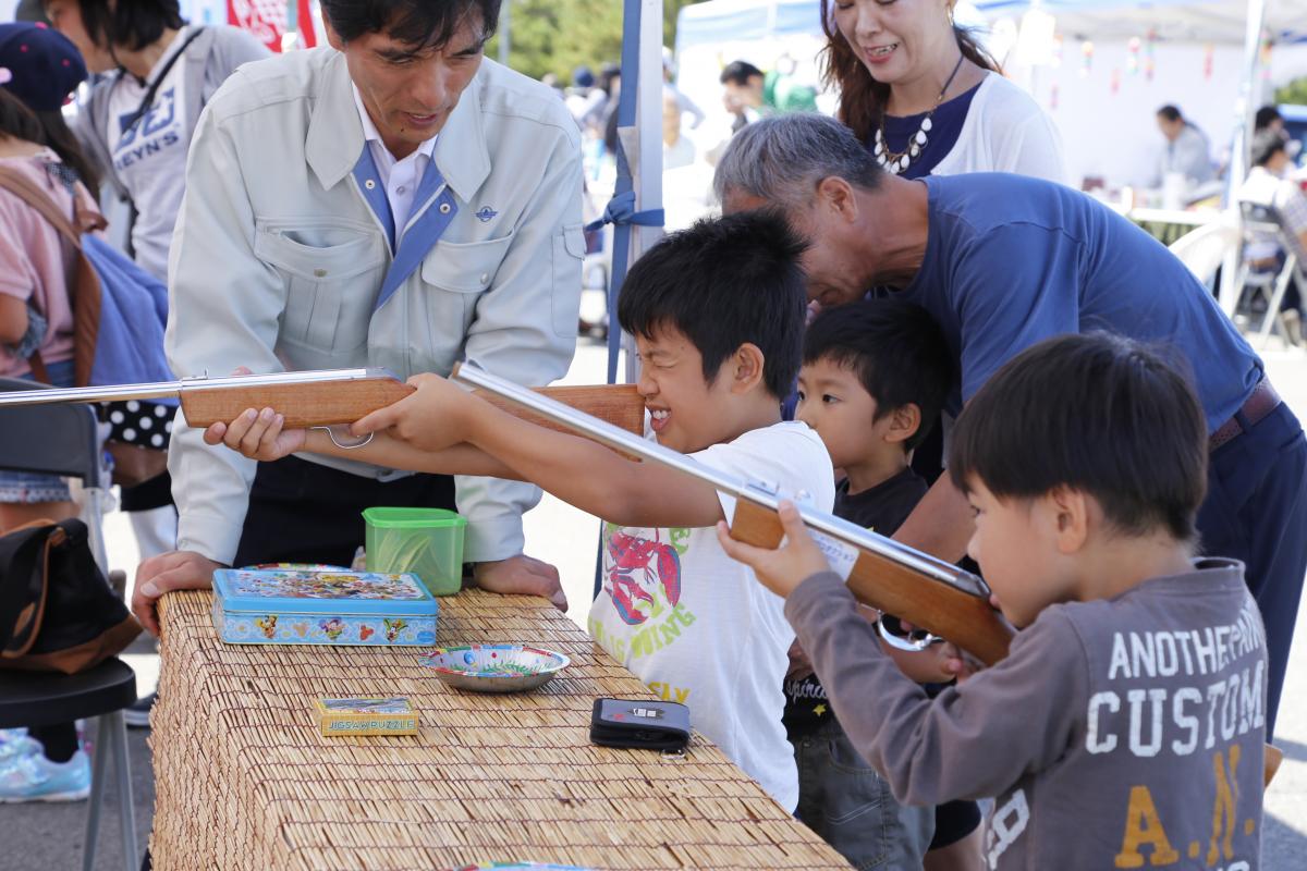 射的のブースで狙いを定める子どもたち