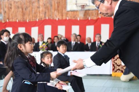 校長先生から新しい教科書を受け取る新1年生