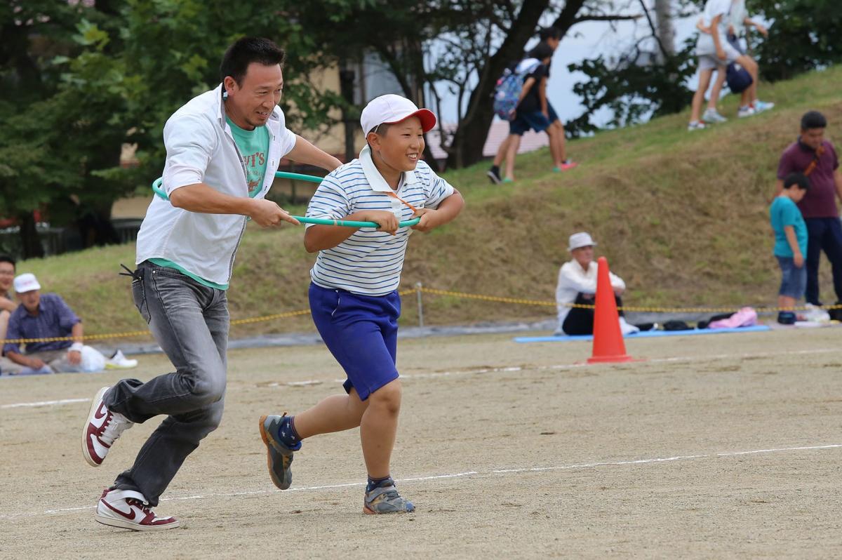 「息を合わせて親子でゴール！」お父さんと1つのフラフープに入りゴールを目指す児童