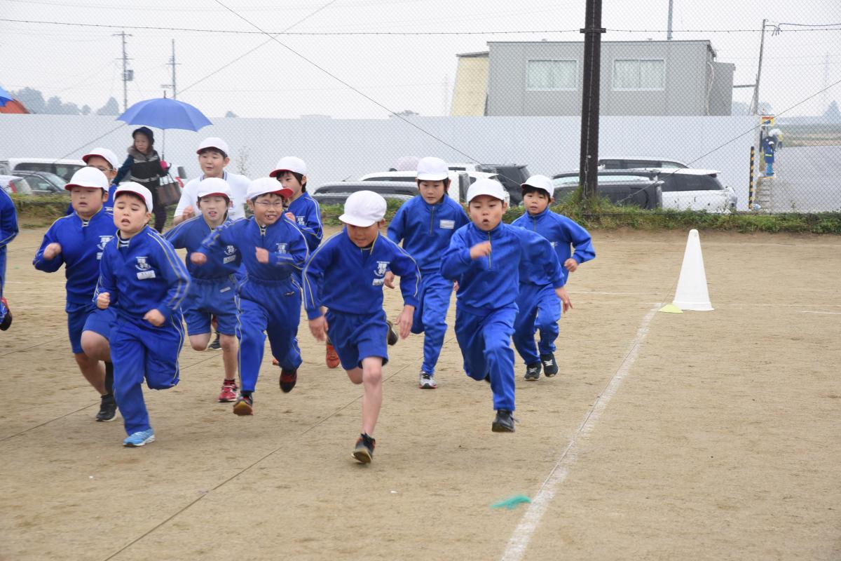 雨の中、懸命に走る児童