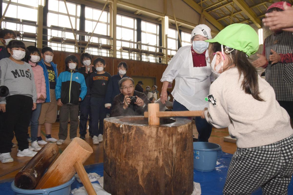 力いっぱい餅をつく園児と、そばで応援する小学生たち