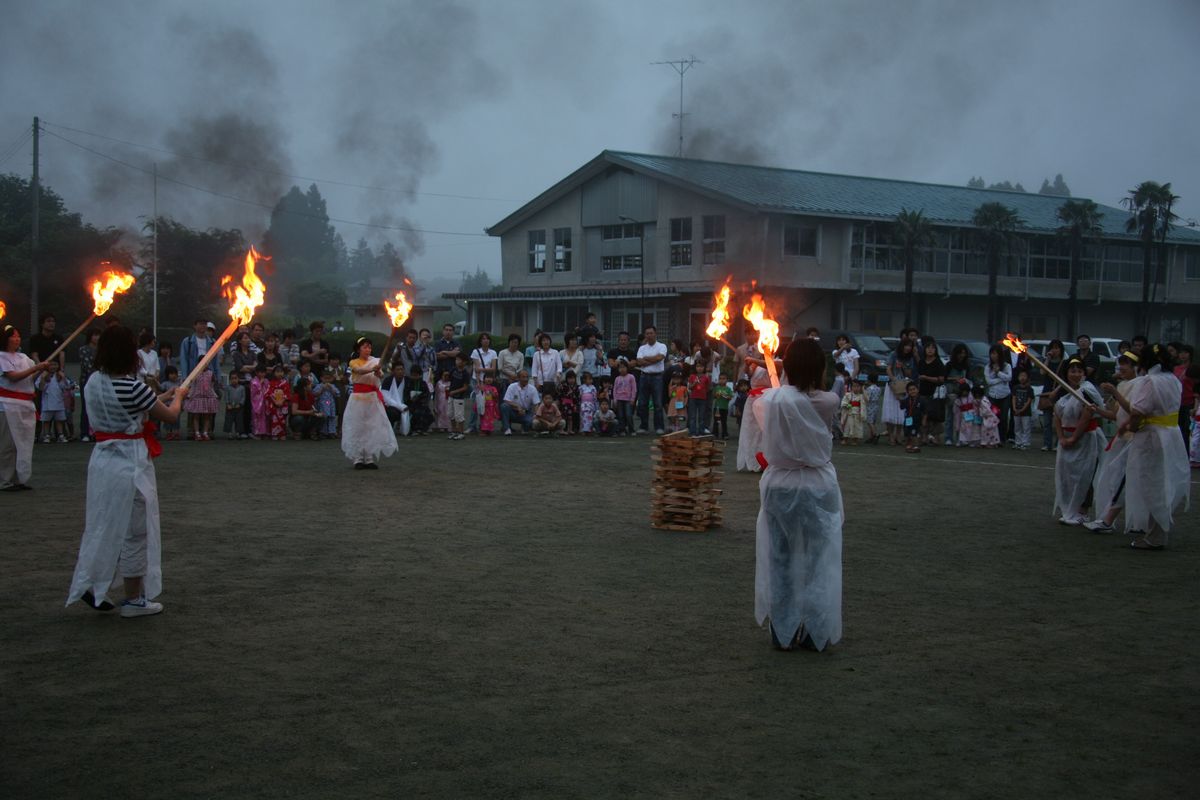 「火の神」が持つたいまつをじっと見つめる園児たち