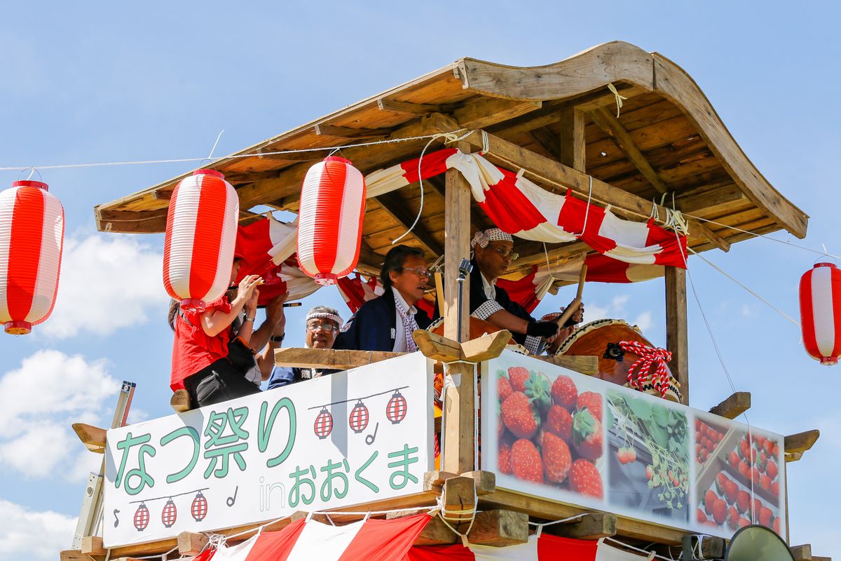 やぐらの上でお囃子を演奏する町民ら