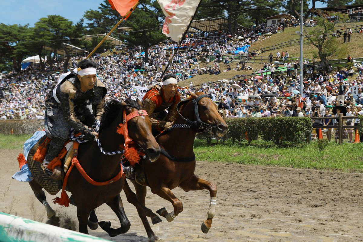 甲冑競馬で先頭争いをしながら場内を駆け抜ける吉田さん（右）