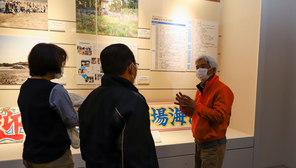 来場者に町の状況を説明する鈴木さん（右）