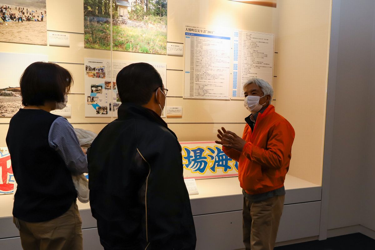 来場者に町の状況を説明する鈴木さん（右）