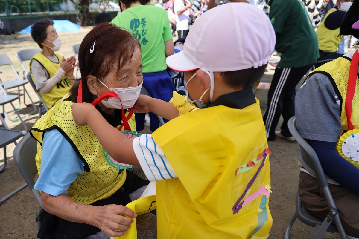 スポーツフェスティバルの参加者にメダルをプレゼントする園児。