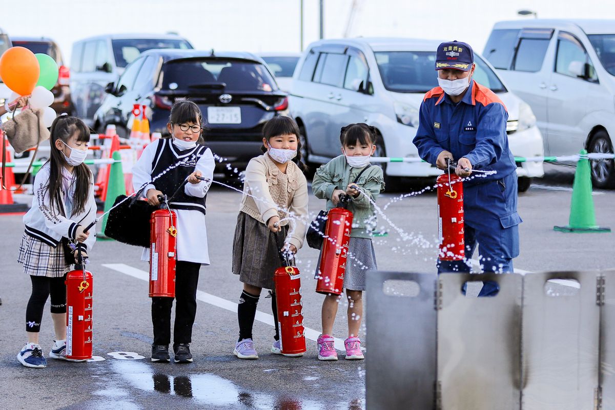 富岡消防署が出展した消火体験コーナーでは消火器の正しい使い方を教えてもらい、子どもたちは実際に赤い炎が大きく燃え上がる中、消火器を片手にしっかりホースを握り炎に向かって噴射しました（今回は体験のため水）。