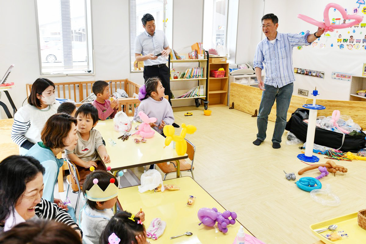 子どもたちに風船作りを披露する坂口さん（右）