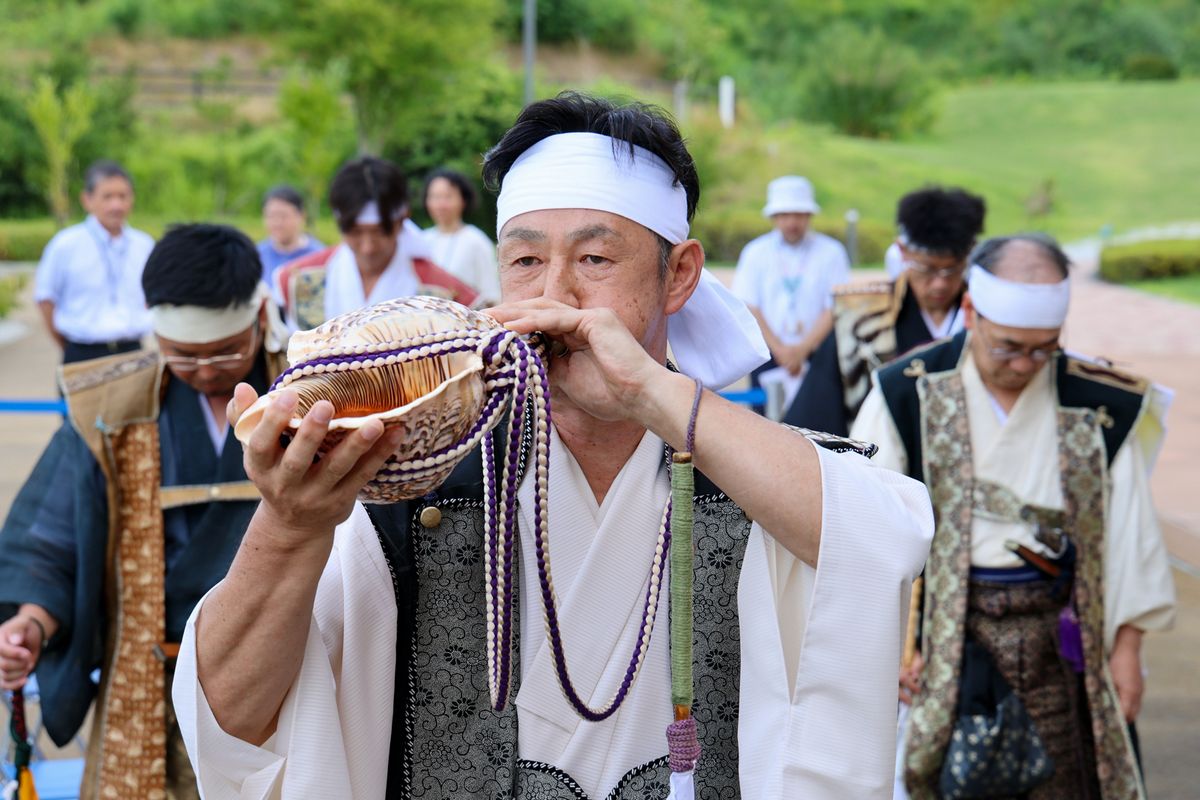 相馬小高神社の方角に向い礼螺（れいがい）を吹く渡部さん