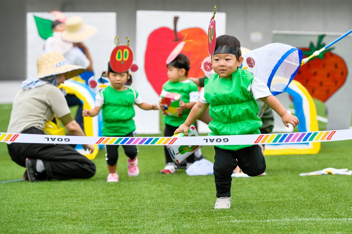 こども園の０～２歳の親子競技「はらぺこあおむしよーいどん」。絵本「はらぺこあおむし」の服装で、自分が取ったものと同じくだもののトンネルをくぐります。