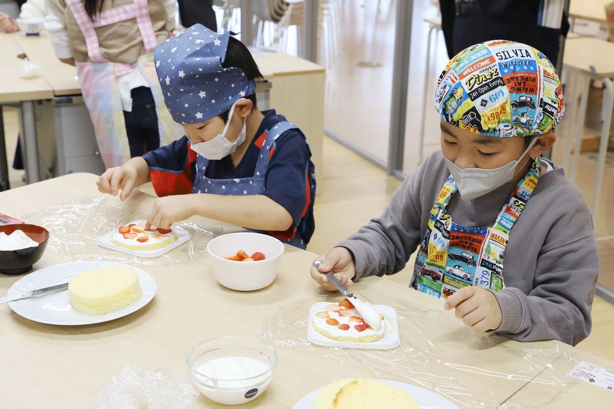 いよいよケーキ作り開始。ナイフで生クリームをすくい取り3等分にスライスされた1段目のスポンジに塗り広げます。その上にイチゴを並べ、また生クリームを塗り広げます。1段目が出来上がると、優しくスポンジを重ね同じ作業を繰り返しました。