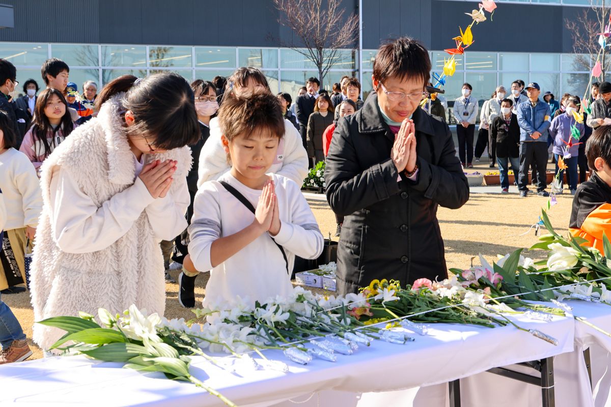 花を手向け祈りを捧げる学び舎ゆめの森の子どもたち。