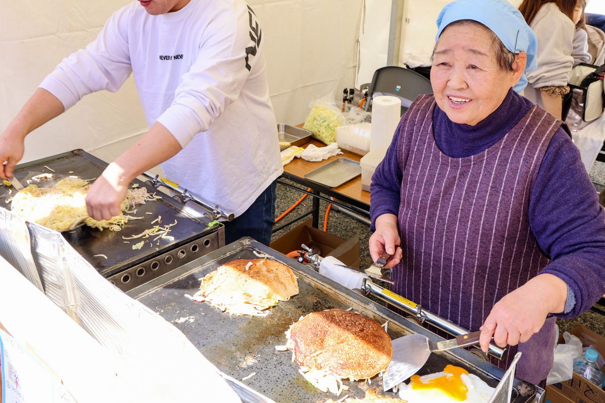 味自慢のお好みやきと焼きそばの旗が掲げられたマルヤス商店の店先には、懐かし味を求めて行列ができました。