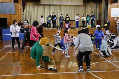 小学校の体育館で鬼に向かって豆まきをする児童たち