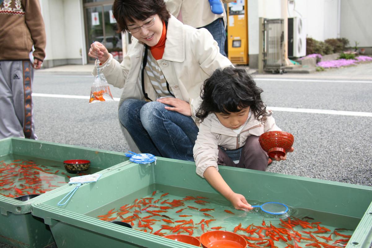 春祭り歩行者天国で金魚すくいを楽しむ親子