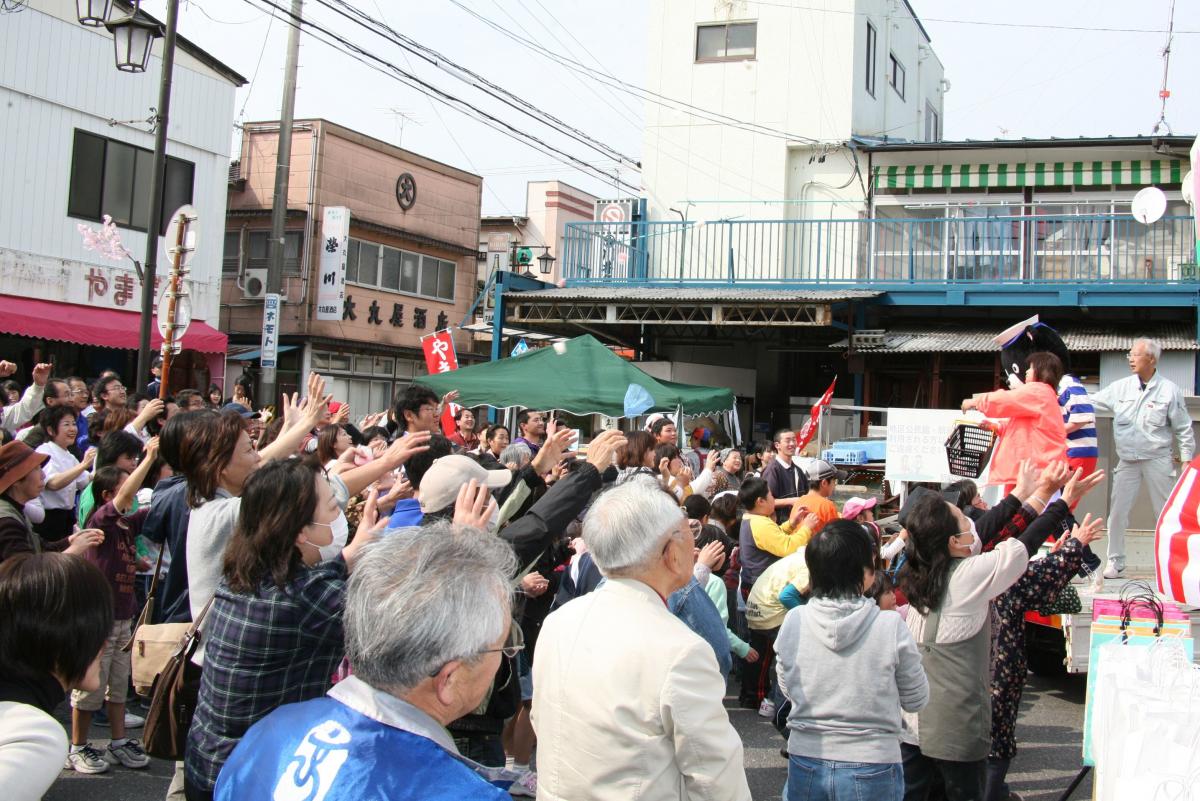 餅まきが始まり、両手を伸ばしキャッチしようとする来場者