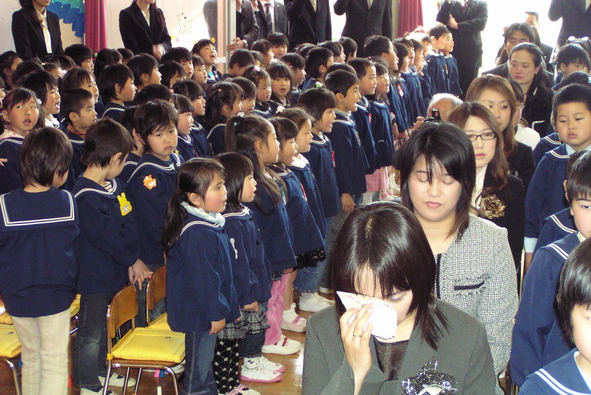 卒園生に向けお祝いの歌を贈る在園児と、ハンカチで涙を拭う走園生の保護者