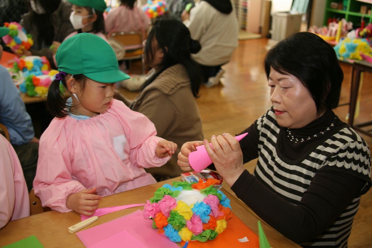 色とりどりの花がたくさん付いた鬼の冠にピンク色のツノを付ける親子