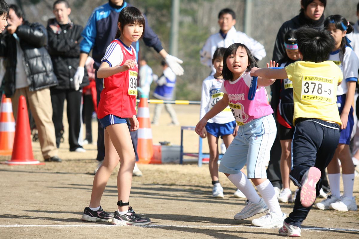 次のランナーにたすきを繋ぐ小学生