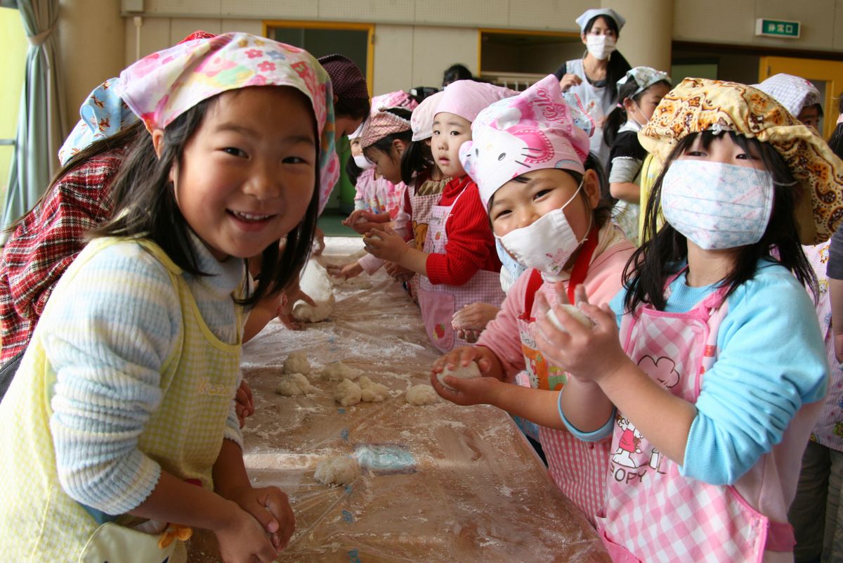 つきあがったもちを丸くまるめる子どもたち