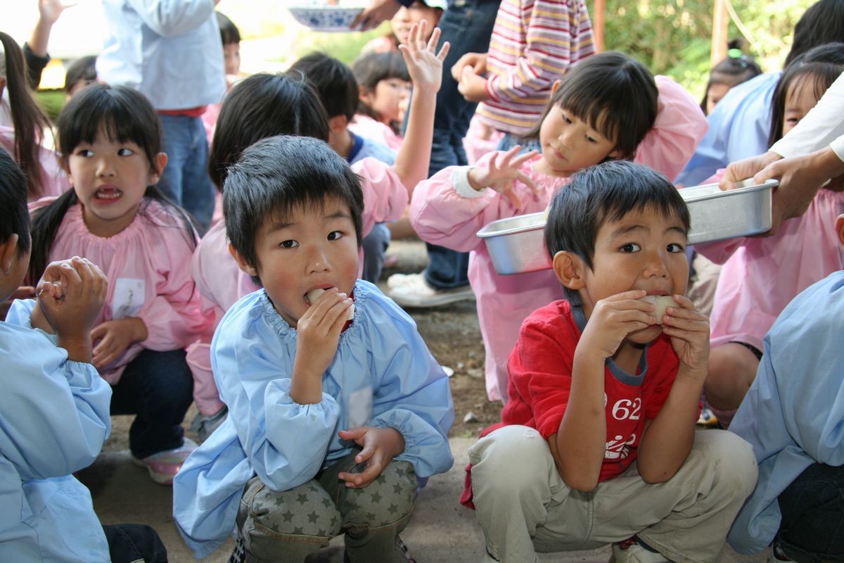 大きなお口を開けて収穫したナシを頬張る園児