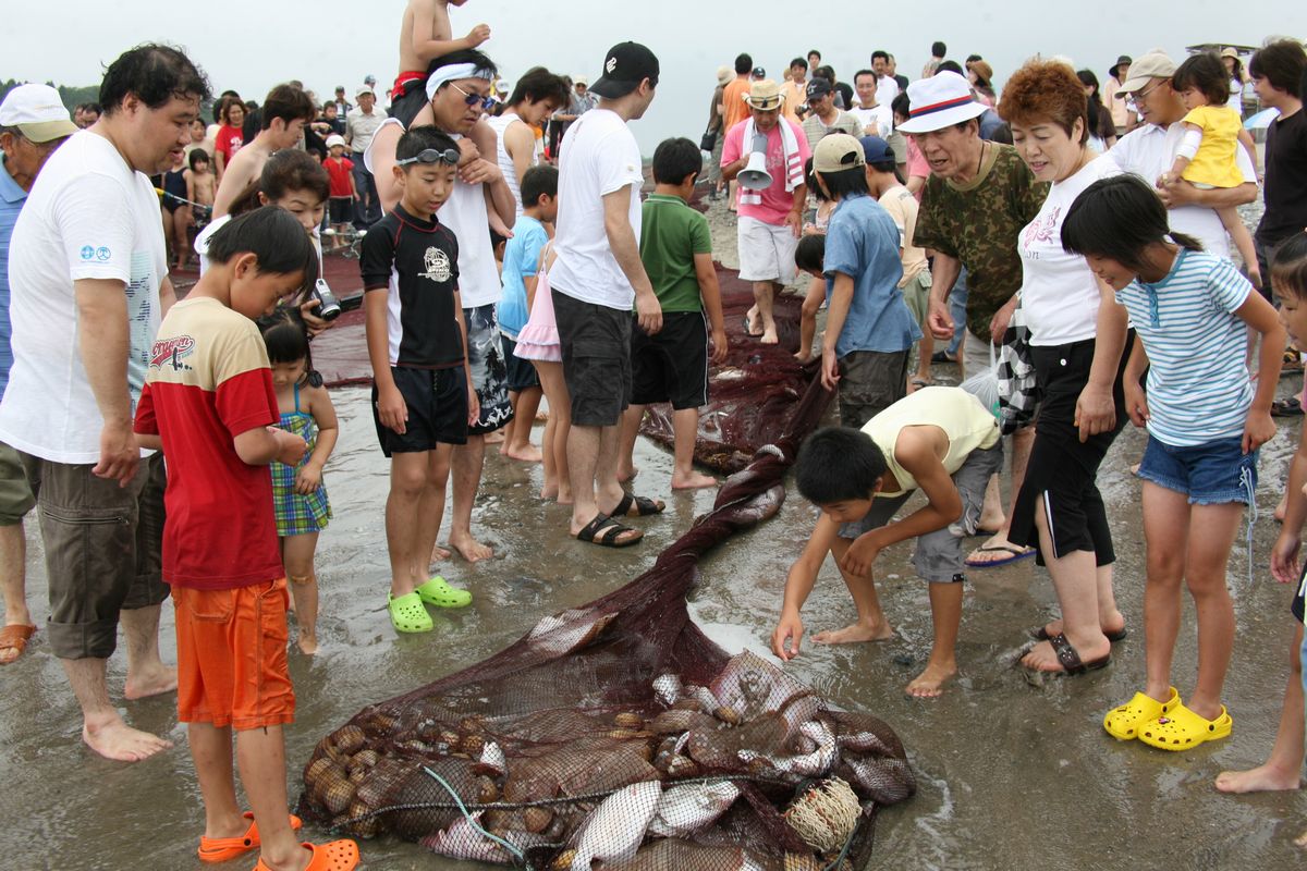 魚や貝がたくさん引き揚がり歓声を上げる海水浴客たち