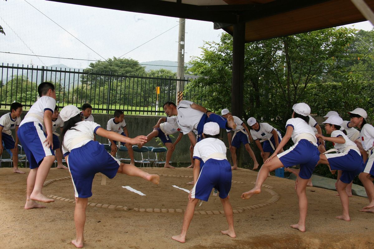 四股踏みを教わり実際に練習する児童たち