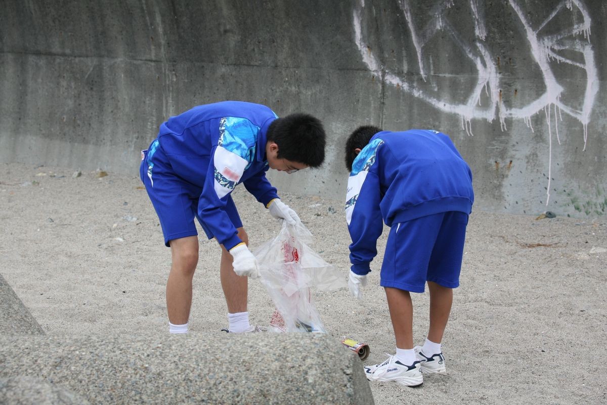 海や川から流れ着いた木くずや海草を拾い集める生徒たち