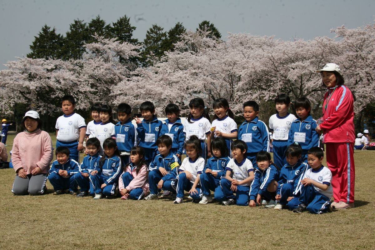 満開の桜を背に記念撮影をする1年生